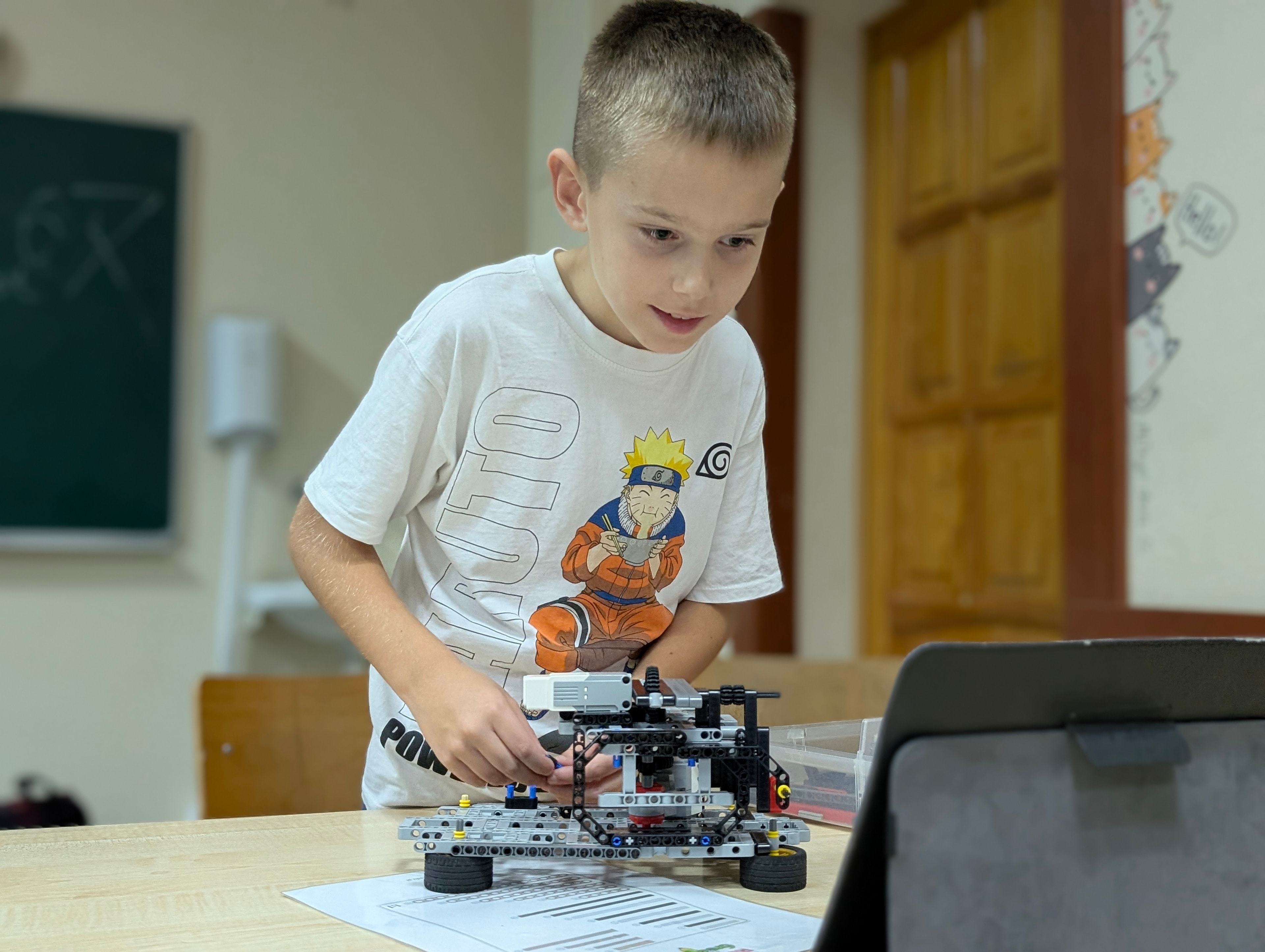 Uczestnik pracuje nad robotem obok tabletu
